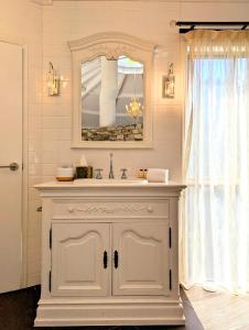 uma casa de banho branca com um lavatório e um espelho em Austinvilla Estate em Mudgeeraba
