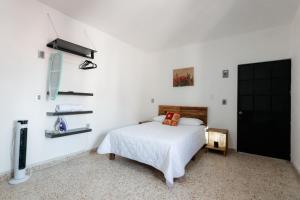 a white bedroom with a bed and a tv at Casa Uxmal de Taxco in Taxco de Alarcón