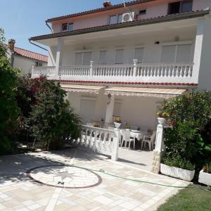 a large white house with a table and a balcony at Apartment Daisy- excellent location close to Rab in Rab