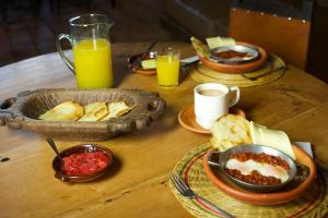 a wooden table with plates of food and cups of orange juice at Hotel Ráquira Silvestre Lodge in Tinjacá