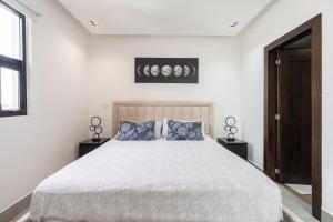 una camera bianca con un grande letto con cuscini blu di Modern Luxury Condo with Rooftop Pool & Gym a Santiago de los Caballeros Altre 10 foto