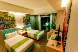 Habitación de hotel con 2 camas y escritorio en Aziza Paradise Hotel, en Puerto Princesa City