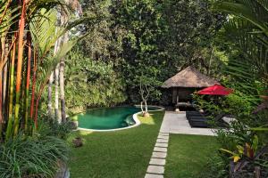 un patio trasero con piscina y cenador en Villa Pangi Gita, en Canggu