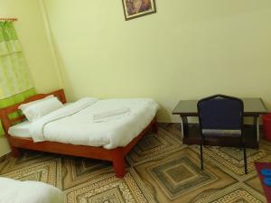 a bedroom with a bed and a desk and a chair at Mangal homestay in Pokhara
