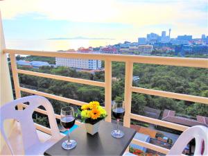 - une table avec deux verres de vin et des fleurs sur le balcon dans l'établissement Sea View Beachfront Condos Pattaya Jomtien Beach, à Jomtien Beach