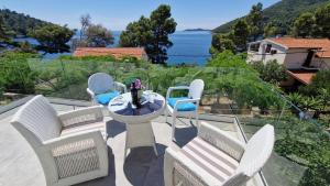 eine Terrasse mit Stühlen und einem Tisch mit Meerblick in der Unterkunft Apartment Mila - 80m to the beach in Brna