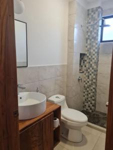 ein Badezimmer mit Waschbecken, Toilette und Dusche in der Unterkunft Rivera Suites El Girasol - Puerto López in Puerto López