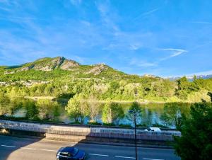 a car parked next to a river with a mountain at Studio 105 - Calme & Tout Equipé avec Parking Gratuit in Grenoble