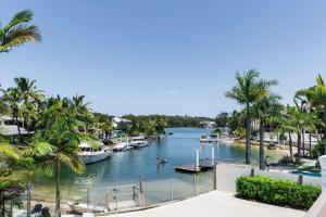 a river with boats in a marina with palm trees at Sunset Sound Noosa in Noosa Heads