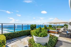 eine Terrasse mit einem Sonnenschirm, Stühlen und Meerblick in der Unterkunft Rhapsody Resort - Official in Gold Coast