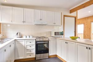 a kitchen with white cabinets and a stove top oven at Freycinet Sanctuary 4 in Coles Bay