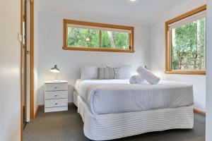 biała sypialnia z 2 łóżkami i oknem w obiekcie Freycinet Sanctuary 4 w mieście Coles Bay