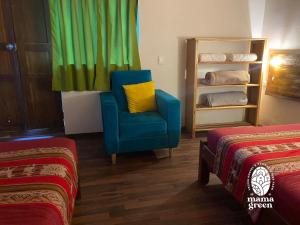 Una silla azul con una almohada amarilla en una habitación con 2 camas en MAMA GREEN Veggie Hostal & Permaculture Farm, en Urubamba