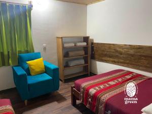 a room with a bed and a blue chair in it at MAMA GREEN Veggie Hostal & Permaculture Farm in Urubamba