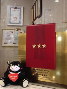 un oso de peluche sentado junto a una caja roja con estrellas doradas en Sa-Yo Hotel - Pier 2 en Kaohsiung