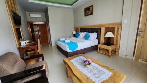 a bedroom with a bed and a table with flowers on it at Toraja Banua Hotel in Rantepao