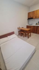 ein weißes Zimmer mit einem Bett und einem Holztisch in der Unterkunft Rivera Suites El Girasol - Puerto López in Puerto López