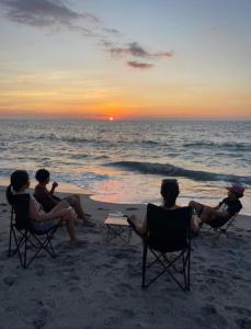 a group of people sitting on the beach watching the sunset at Kavvayi Kayaloram The Arabian Beach House in Kokkānisseri