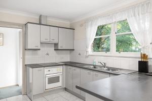 una cucina con mobili bianchi e un lavandino di Detached Queen Room in Pymble - Serene Spot - Shared Bathroom a Pymble