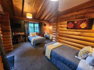 a room with three beds in a log cabin at Rainforest Retreat in Franz Josef
