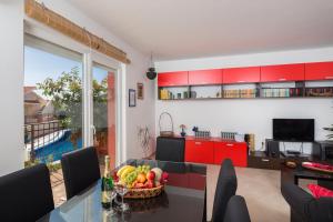 una cucina con armadi rossi e un tavolo con un cesto di frutta di Laura Apartment a Trogir