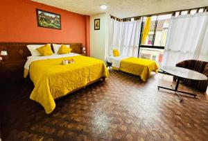 a hotel room with two beds and a table at Hotel Las Americas in Cuenca