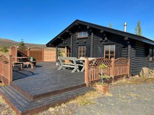 une cabane en rondins noirs avec une terrasse en bois dans l'établissement Cosy cabin with amazing view on the Geysir, à Blaskogabyggo