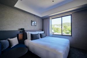 una camera da letto con un grande letto bianco e una finestra di NOHGA HOTEL KIYOMIZU KYOTO a Kyoto