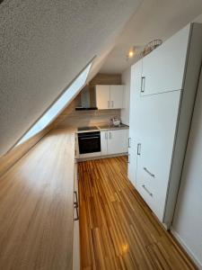 a kitchen with white cabinets and a kitchen with wooden floors at Sonnenschein Chalet in Buxheim