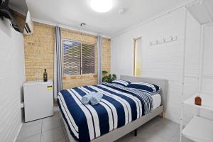 1 dormitorio con 1 cama con rayas azules y blancas en Motel Sunshine Coast, en Caloundra