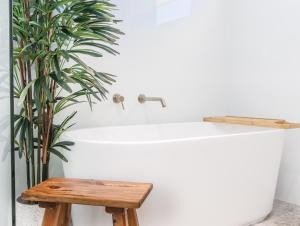 a bathtub with a wooden stool next to a plant at Coastal Home, 500m Walk to Hospital with Ocean Views in Kingscliff +10 photos