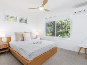 a white bedroom with a bed and two windows at Coastal Home, 500m Walk to Hospital with Ocean Views in Kingscliff