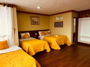 um quarto de hotel com duas camas com lençóis amarelos em Hotel Las Americas em Cuenca