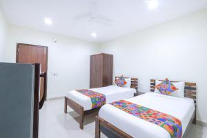 two beds in a room with white walls at FabHotel SK Grand in Hyderabad