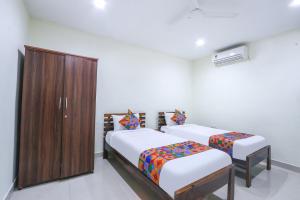 a bedroom with two beds and a wooden cabinet at FabHotel SK Grand in Hyderabad