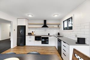 a kitchen with white cabinets and a black refrigerator at 5 Min Stroll into Town Centre - No Hills in Queenstown