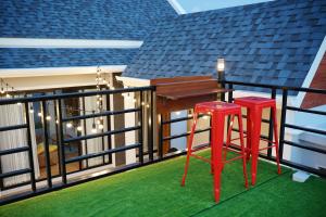 a balcony with two red stools and a table at Nattarin Pool Villa Pattaya-Na Chom Thian in Ban Map Fakthong