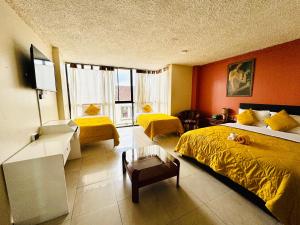 昆卡的住宿－Hotel Las Americas，酒店客房带两张带黄床单的床