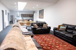 a living room with two couches and a table at Alpine Junction Townhouse Apartments, Lodge & Hotel in Wanaka