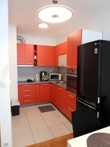 a kitchen with red cabinets and a black refrigerator at AppLuna in Zagreb