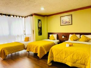 クエンカにあるHotel Las Americasのホテルルーム 黄色いシーツ付きのベッド2台付