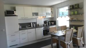 eine Küche mit weißen Schränken und einem Tisch mit Stühlen in der Unterkunft Talstation in Braunlage