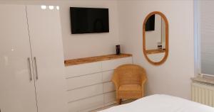 ein Schlafzimmer mit einem TV, einem Stuhl und einem Spiegel in der Unterkunft Talstation in Braunlage