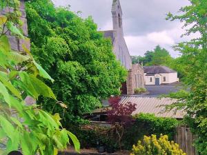 a church with a steeple and a yard with plants at Church View House in Gorteen