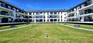 an apartment building with a playground in the middle of a yard at Apartament Perła Jantaru by TriApart in Jantar