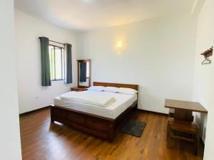 a bedroom with a bed and a wooden floor at Kottagala White House in Kotagala