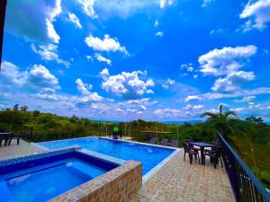 a swimming pool with a blue sky with clouds at Hotel Campestre Atardecer Cafetero in Quimbaya
