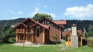 una casa de madera con chimenea en un campo en АртГір гостинний двір, en Mykulychyn
