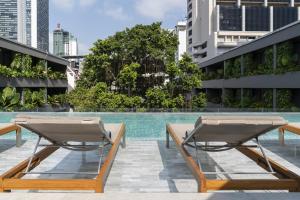 - une piscine avec 2 chaises longues à côté d'un bâtiment dans l'établissement Ad Lib Hotel Bangkok, à Bangkok