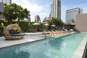 - une piscine avec des chaises, des tables et des parasols dans l'établissement Ad Lib Hotel Bangkok, à Bangkok